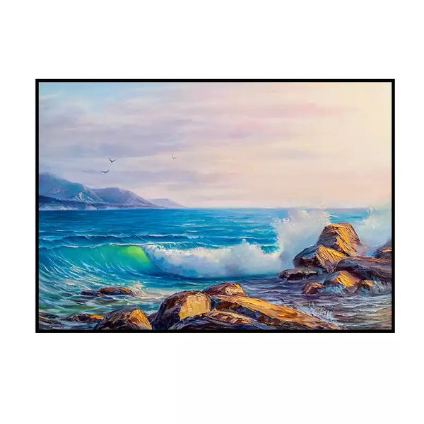 A large horizontal wall art of blue waves splashing onto the rocks on the shore, with a few sea birds flying on the horizon in the pink sky. 