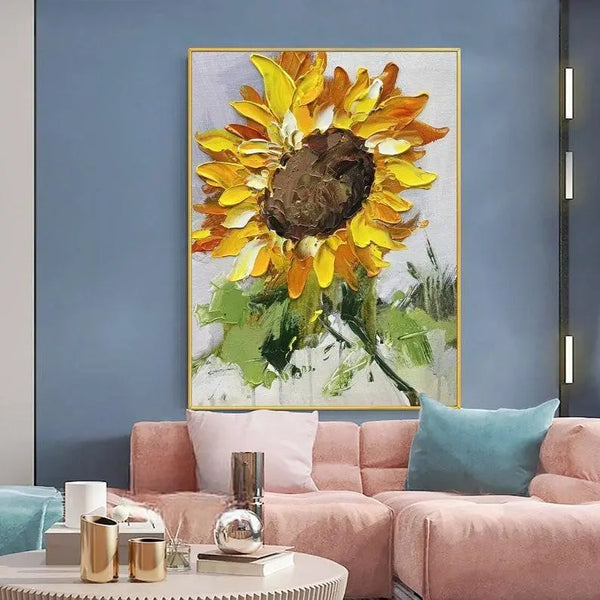 A large textured painting of a yellow sunflower with green leaves on a gray canvas.  
