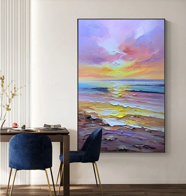 A large vertical textured wall painting of purple textured beach with blue ocean, bathed in the yellow sunlight beneath the purple sky. 