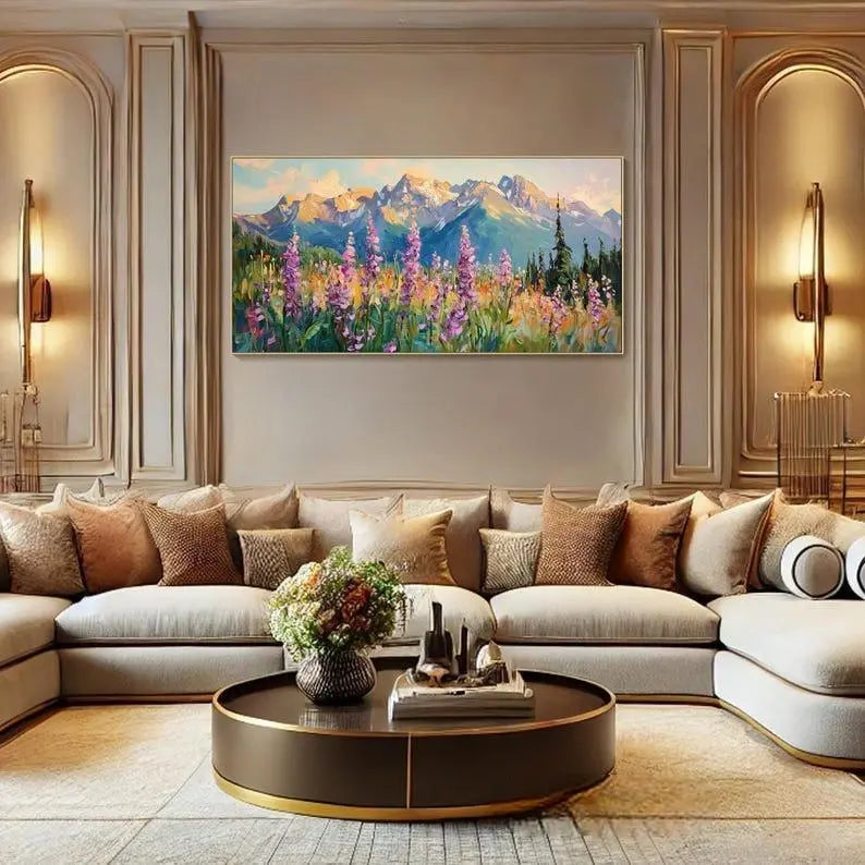 A large textured horizontal painting of rolling mountains under the blue sky with white clouds on the background, and pink flowers on the foreground. 