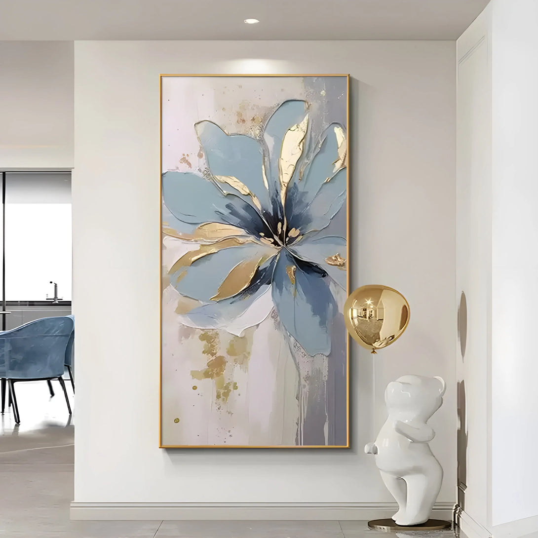 A large vertical abstract painting of a flower in blue and gold, with a touch of black, against a white backdrop. 
