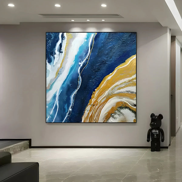 A colorful abstract ocean painting with textured blue and yellow waves seen from above, blending into a shoreline, in a square layout.