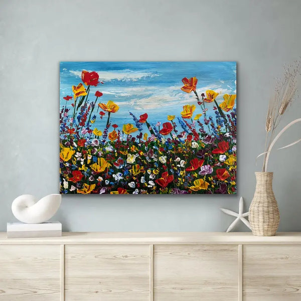  A horizontal abstract painting of a colorful wildflower landscape with textured orange, red, and blue tones.