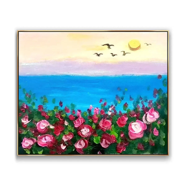 A large horizontal painting featuring the blue sea bordered by the shore full of blooming pink flowers amidst greenery. On the horizon is the yellow-hued sky with a few sea birds. 
