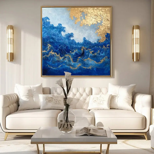 A large square painting featuring the rough blue sea waves under a tree with gold leaves. 