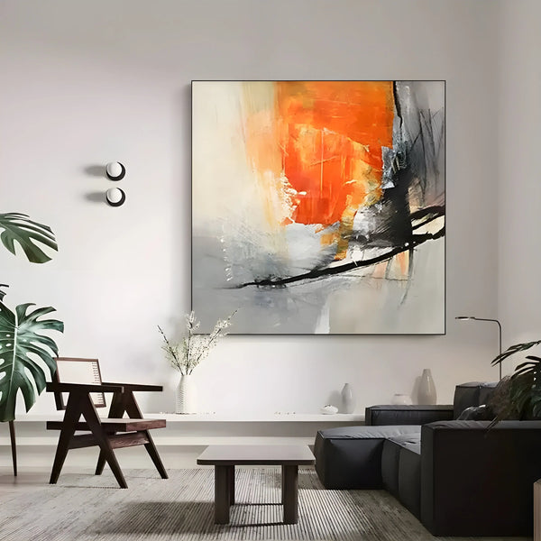 A large square painting mixing orange and black acrylic layers against a grey backdrop. 