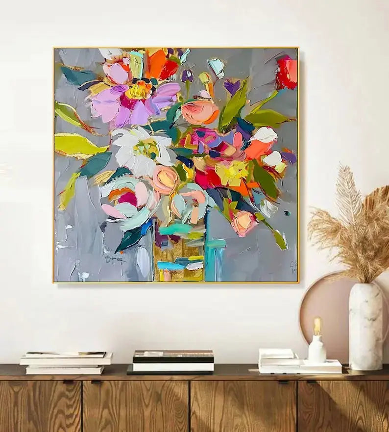 A large square painting of pink, yellow, purple, white and orange abstract flowers, painted with layers of acrylics, against a grey backdrop