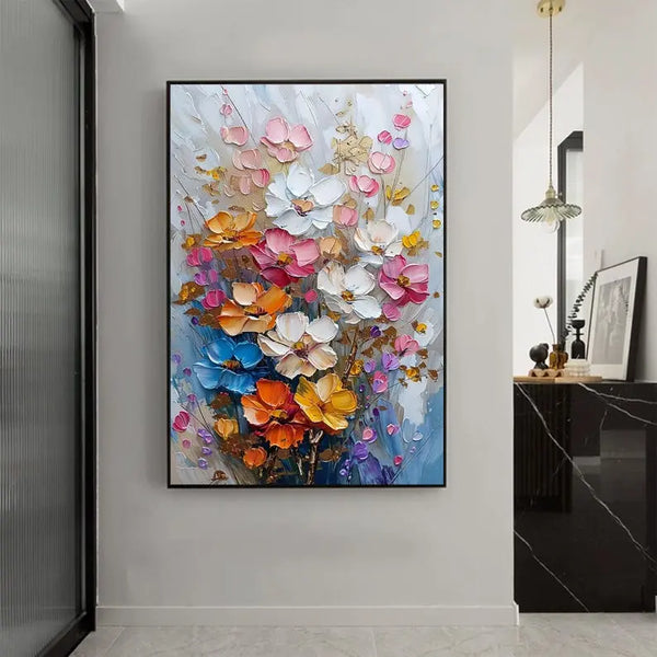 A large textured wall art of flowers in pink, white, blue, yellow and orange with yellow leaves, against a grey and blue backdrop. 