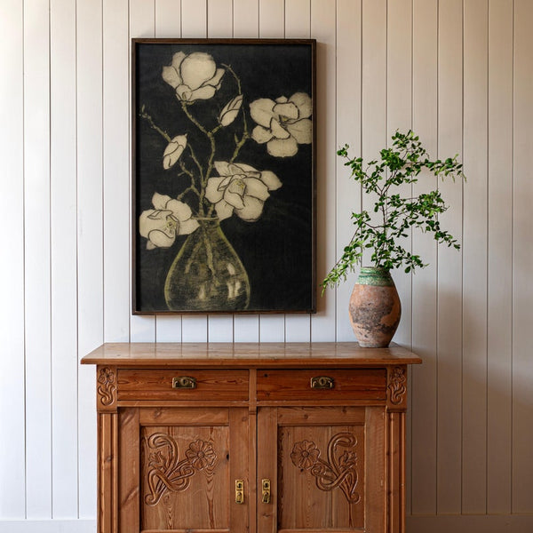 A large vertical painting of yellowish orange flowers in a bottle, against a backdrop of dark jungle green and black. 
