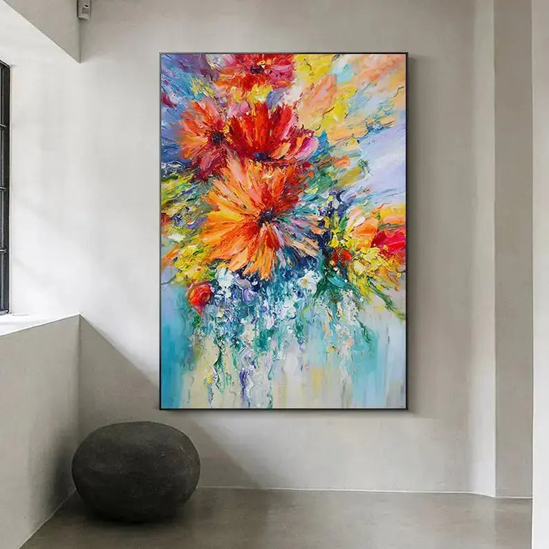 A large vertical painting with bursting orange flowers in plasters, against a blue backdrop.