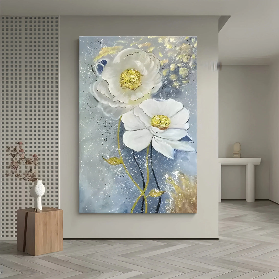  A large vertical textured floral painting of two white plastered flowers with gold pistils, against a light blue backdrop dotted with yellow hues. 
