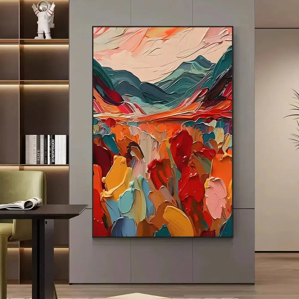 A large vertical textured painting of blooming abstract flowers in red, orange, pink, blue and green hues, and blue mountains under pink sky on the horizon. 
