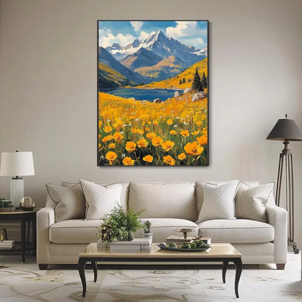 A large vertical textured wall art of a field of yellow flowers in the foreground, leading to a serene lake and softly rolling blue mountains under a luminous, cloud-streaked sky.