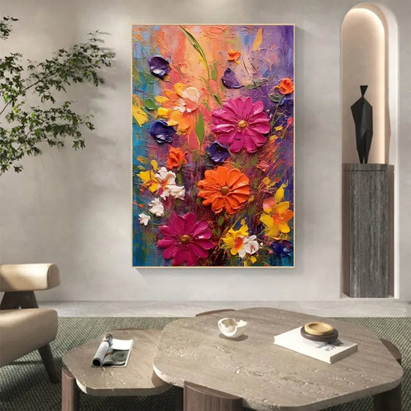 A large vertical textured wall art of flowers in rich plasters in pink, orange and yellow against a backdrop of purple, orange and blue hues. 