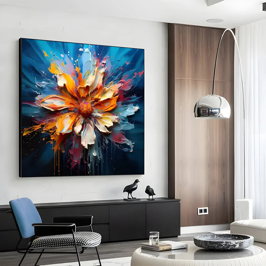 A square abstract painting of a large white and orange flower in the middle of a blue canvas. 