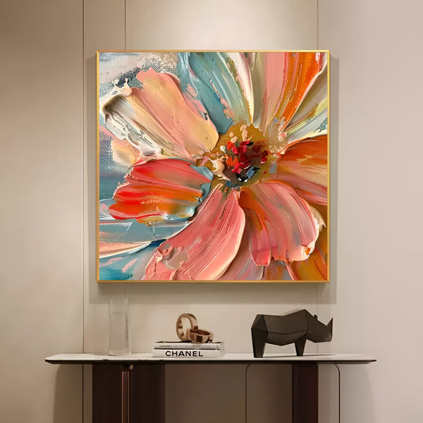 A large square abstract painting of a big blooming red and orange flower against the blue backdrop. 
