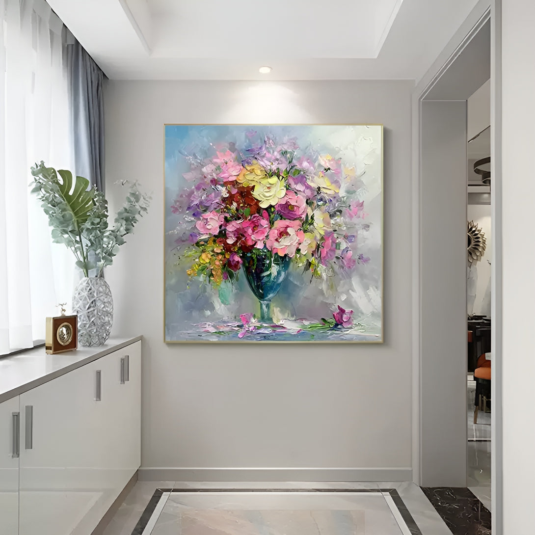 A large square abstract painting with pink, yellow, orange flowers in a blue glass 