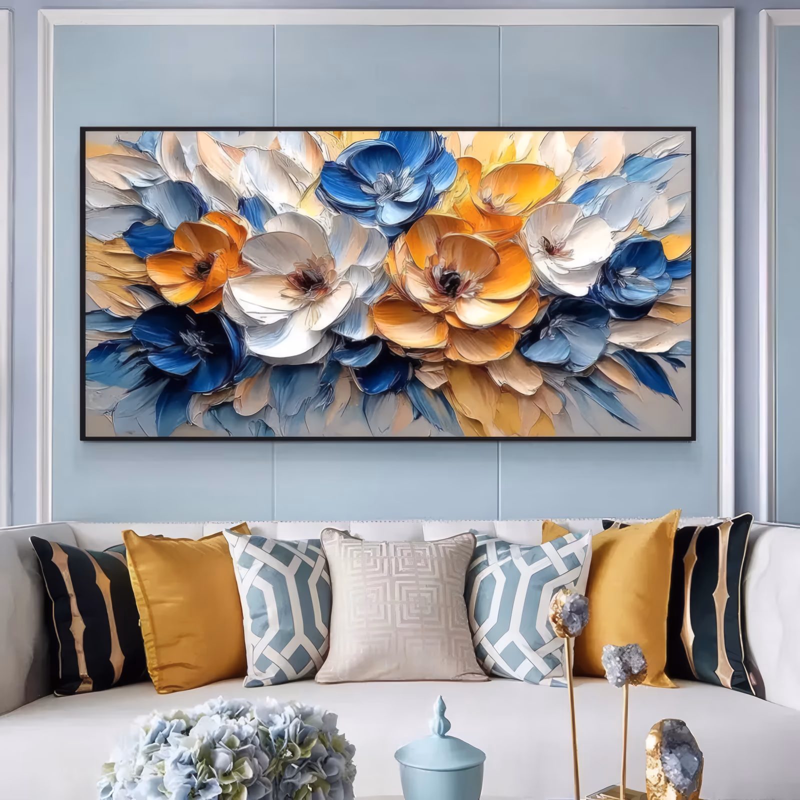 an oversized horizontal floral painting of overlapping blossoms in cream, amber, orange and deep blue, with thick knife-cut petals massed along the full width and dark blue leaves below
