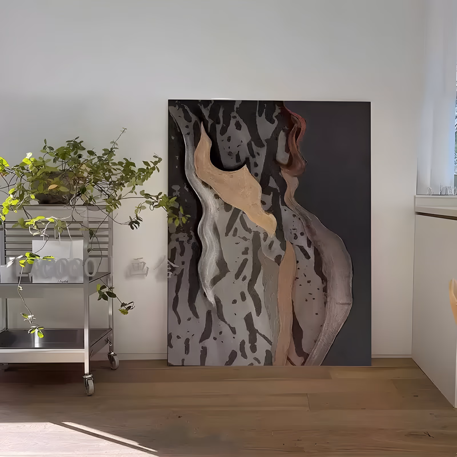 a large vertical relief wall art piece of a stylized female torso, its raised beige and tan forms rising up the center with a rust accent at top right, on a black ground with gray bark-like marks, in raised paste