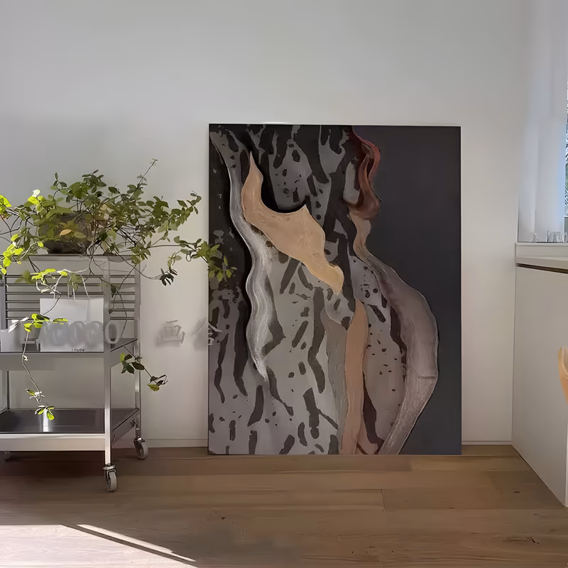 a large vertical relief wall art piece of a stylized female torso, its raised beige and tan forms rising up the center with a rust accent at top right, on a black ground with gray bark-like marks, in raised paste