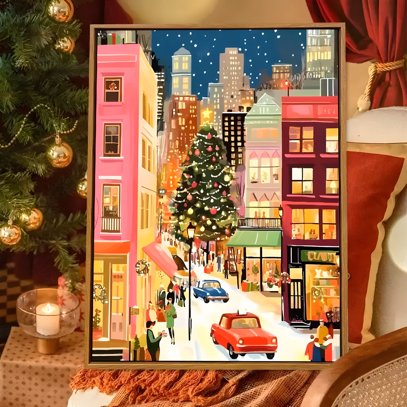 a large vertical illustrated painting of a snowy christmas city street lined with pink and red shopfronts and lit windows, a decorated tree at the center and vintage red and blue cars on the white road