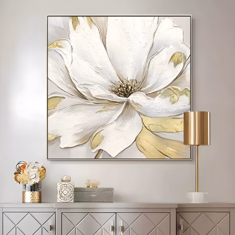 a large square textured floral painting of one oversized white magnolia bloom filling the frame, gold-brushed olive leaves behind it and a cluster of gold stamens at its center, in thick sculpted petals