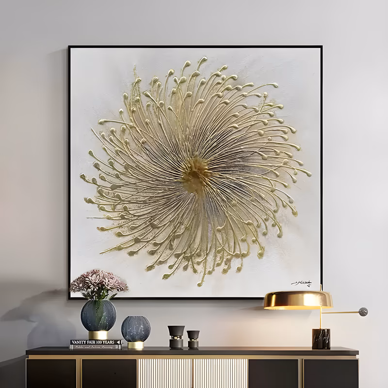 a large square textured floral wall art of a single dandelion seed head, hundreds of fine gold stems radiating from a raised center to pin-shaped tips, sculpted in relief on a plain white ground