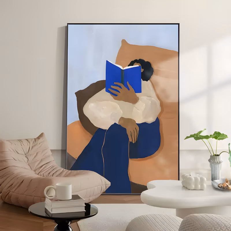 a large vertical figurative painting of a woman curled in a terracotta armchair, a cobalt blue book held up over her face, cream sweater and blue trousers against a pale blue wall, in flat matte oil