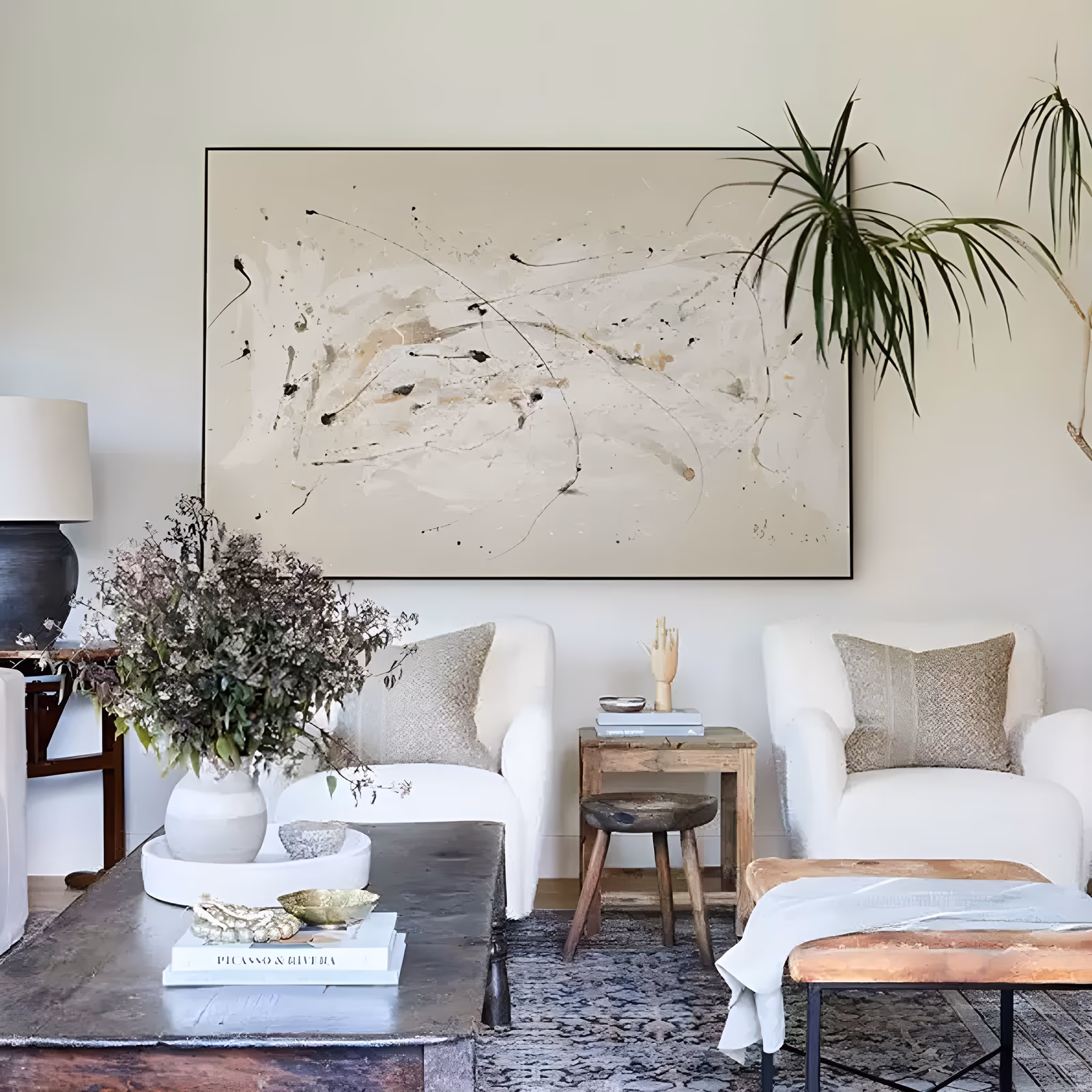 a large horizontal abstract painting of black ink splatter, drips and long thin trailing lines scattered over a soft cream and beige ground, the marks gathering toward the center, in fluid hand-painted acrylic