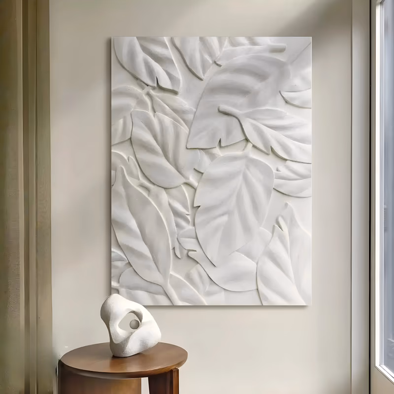 a large vertical white-on-white relief panel of broad overlapping leaves in layers, veins pressed into each blade and no color at all beyond the shadows, in hand-troweled plaster
