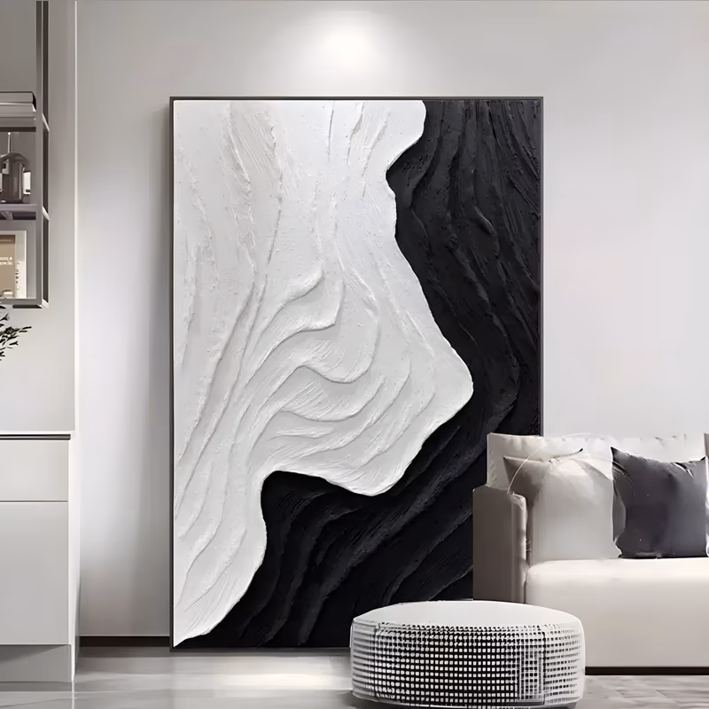 a large vertical black and white relief painting of a thick white plaster wave form curving down the left side against a rough black field on the right, in deep sculpted plaster