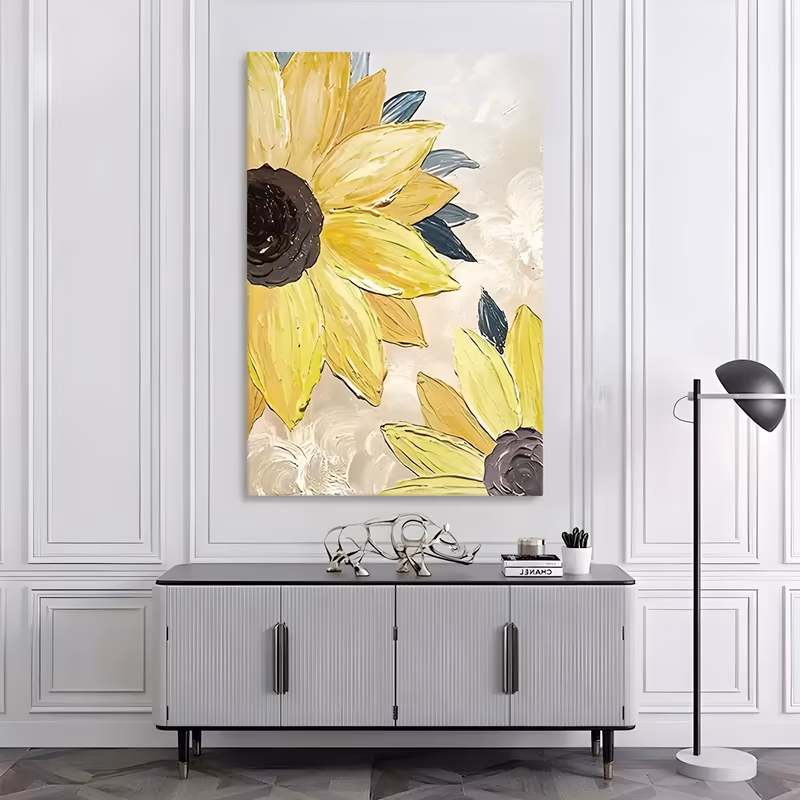 a tall vertical impasto floral painting showing two oversized pale yellow sunflowers in close-up at the left edge, their dark brown centers ringed by thick knife-laid petals, with slate blue leaves on a cream ground