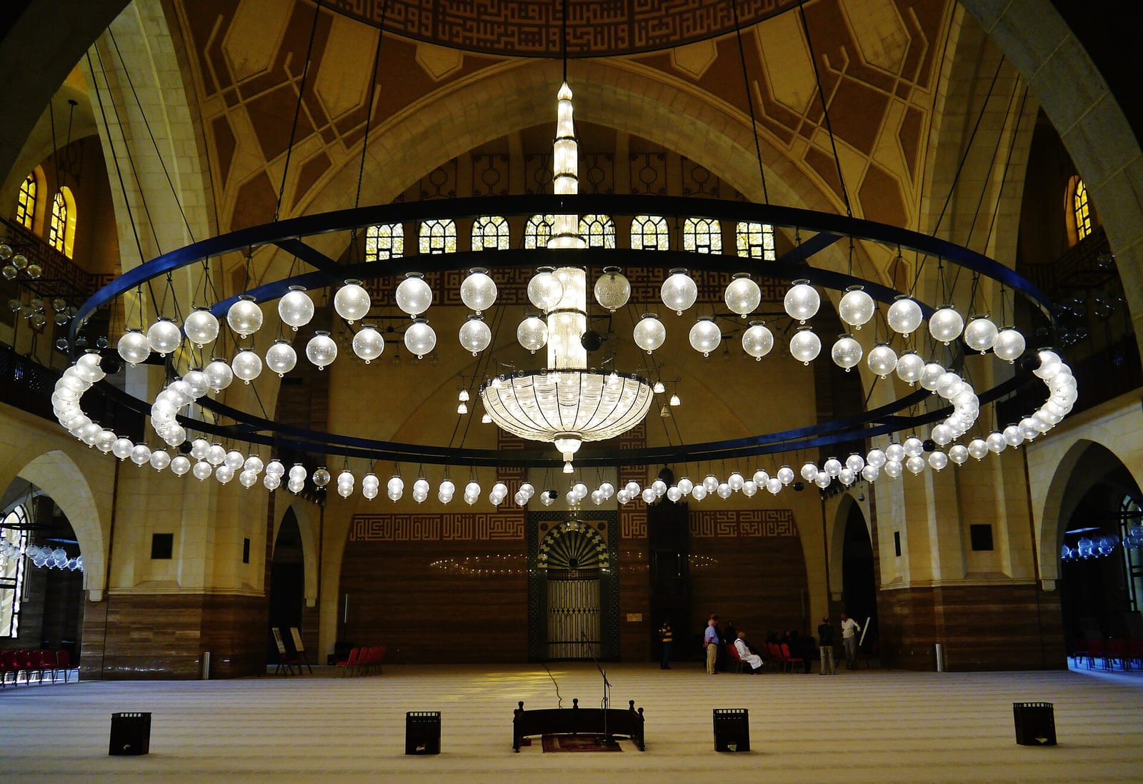 The prayer hall of Al Fateh Grand Mosque in Manama with its carved calligraphy bands, arches and chandelier.
