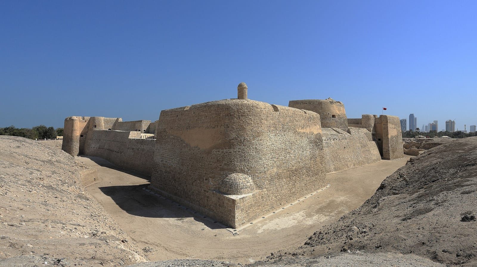 Qal'at al-Bahrain, the UNESCO-listed Bahrain Fort, with its coral-stone ramparts under a clear sky.