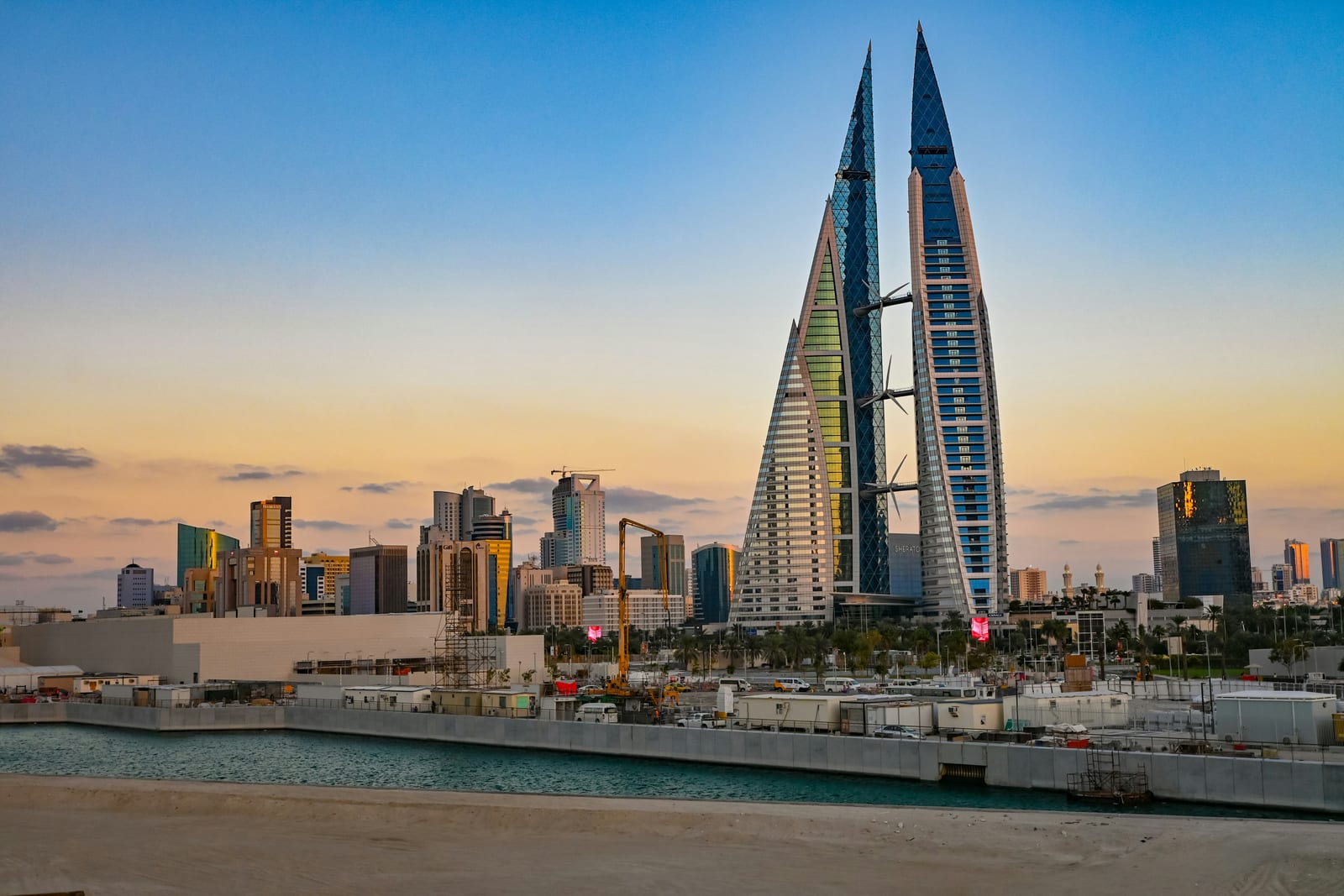 The twin sail-shaped towers of the Bahrain World Trade Center with their wind turbines at sunrise, Manama, May 2025.