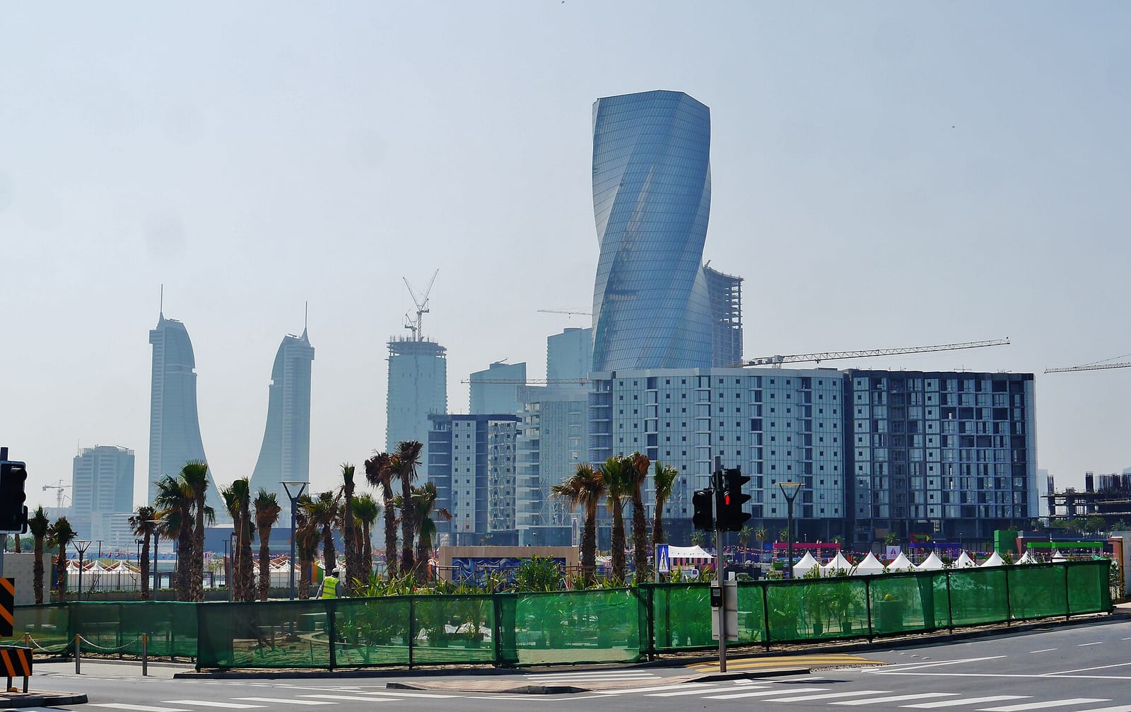 The twisted United Tower and the Financial Harbour towers rising over Bahrain Bay, with new blocks under construction in the foreground.