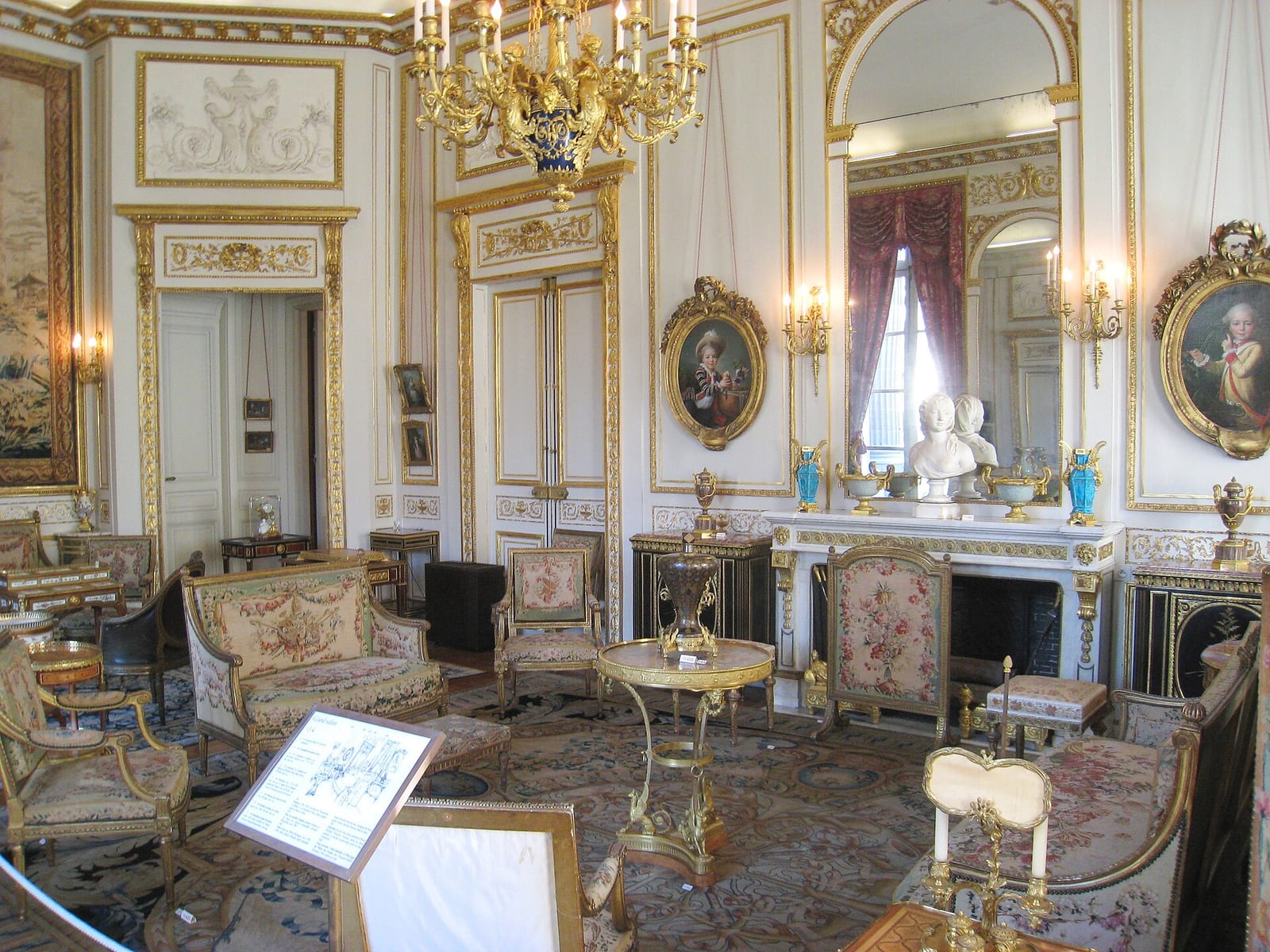 Grand salon of the Musée Nissim de Camondo, Paris, with gilded panelling, silk-covered seats and paintings hung on the boiserie.