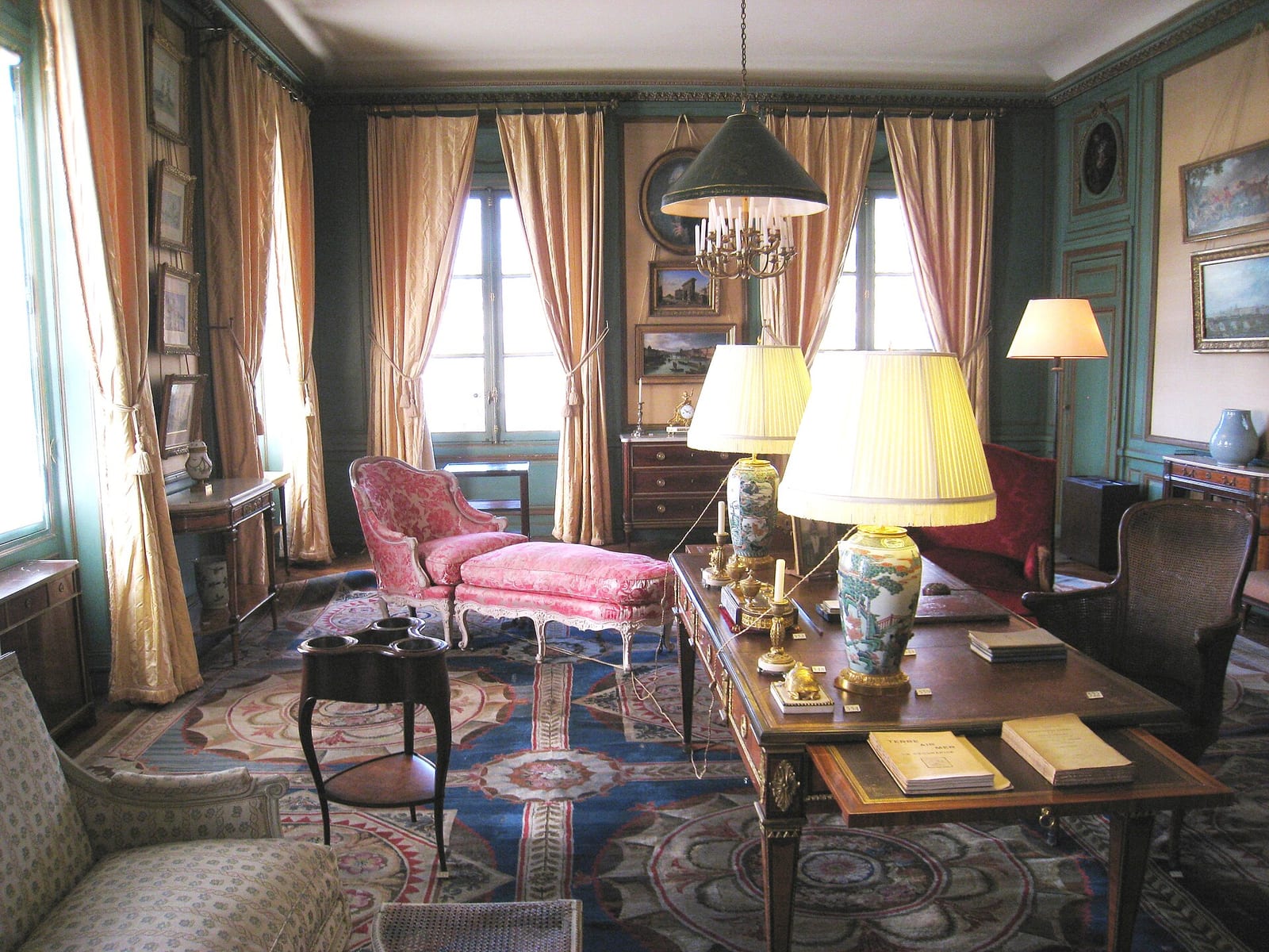 The Salon Bleu at the Musée Nissim de Camondo, Paris, a panelled room with tall curtained windows, lamps and a writing desk.