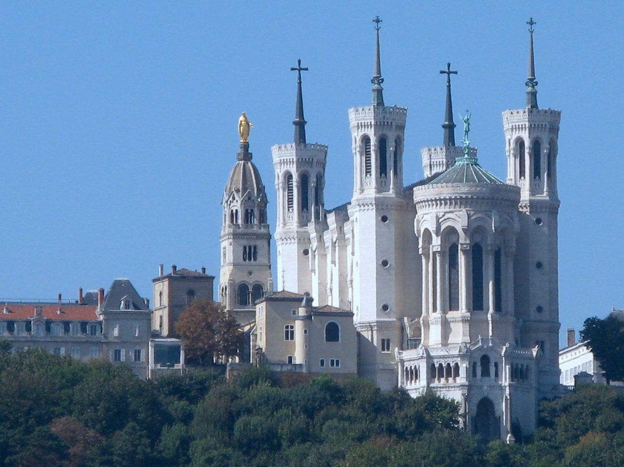 The white towers of the Basilica of Notre-Dame de Fourvière above the Saône quays in Lyon on a bright day.