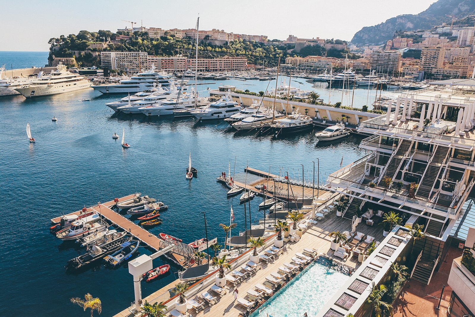 Monaco’s high-rise apartment towers stacked up the hillside above the sea in spring sunshine.