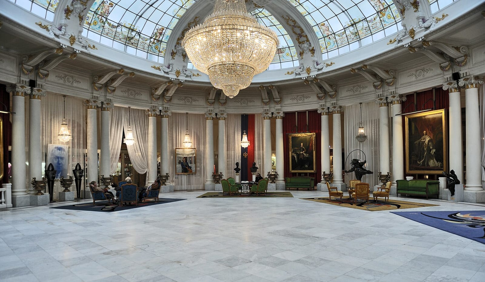 The domed central hall of the Hôtel Negresco in Nice with its chandelier, marble floor and large paintings on the walls.