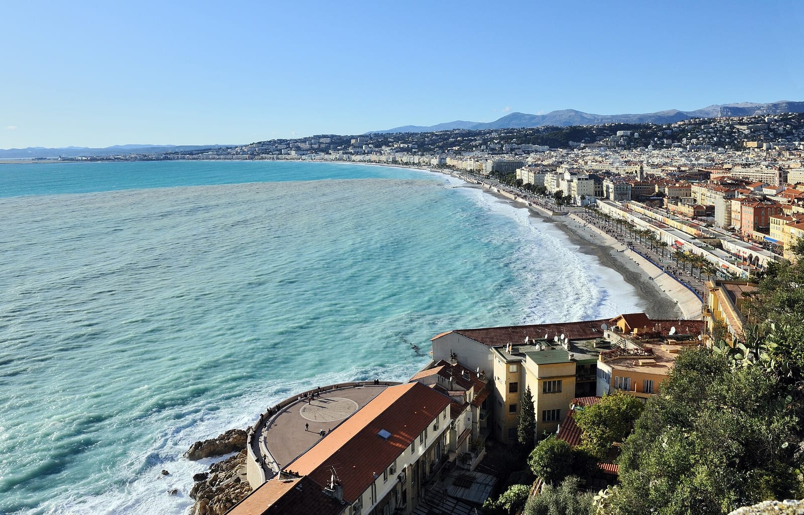 The curve of the Baie des Anges in Nice seen from the castle hill, the Promenade des Anglais running along the shore.