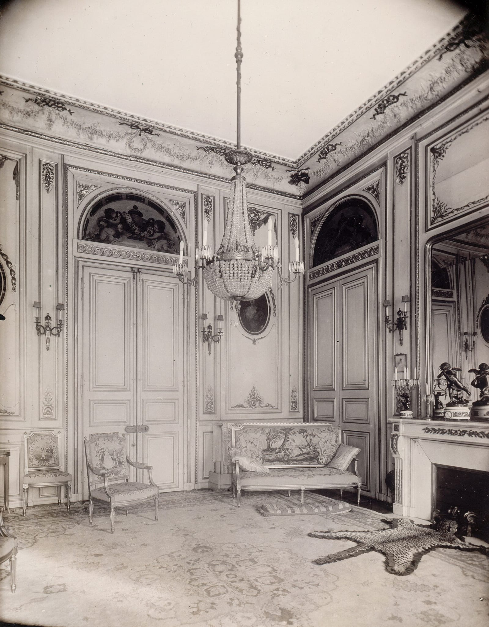 Early-1900s photograph of the grand salon of the Hôtel Caulet d’Hauteville on Place des Vosges, Paris, showing carved panelled doors and an overdoor painting.