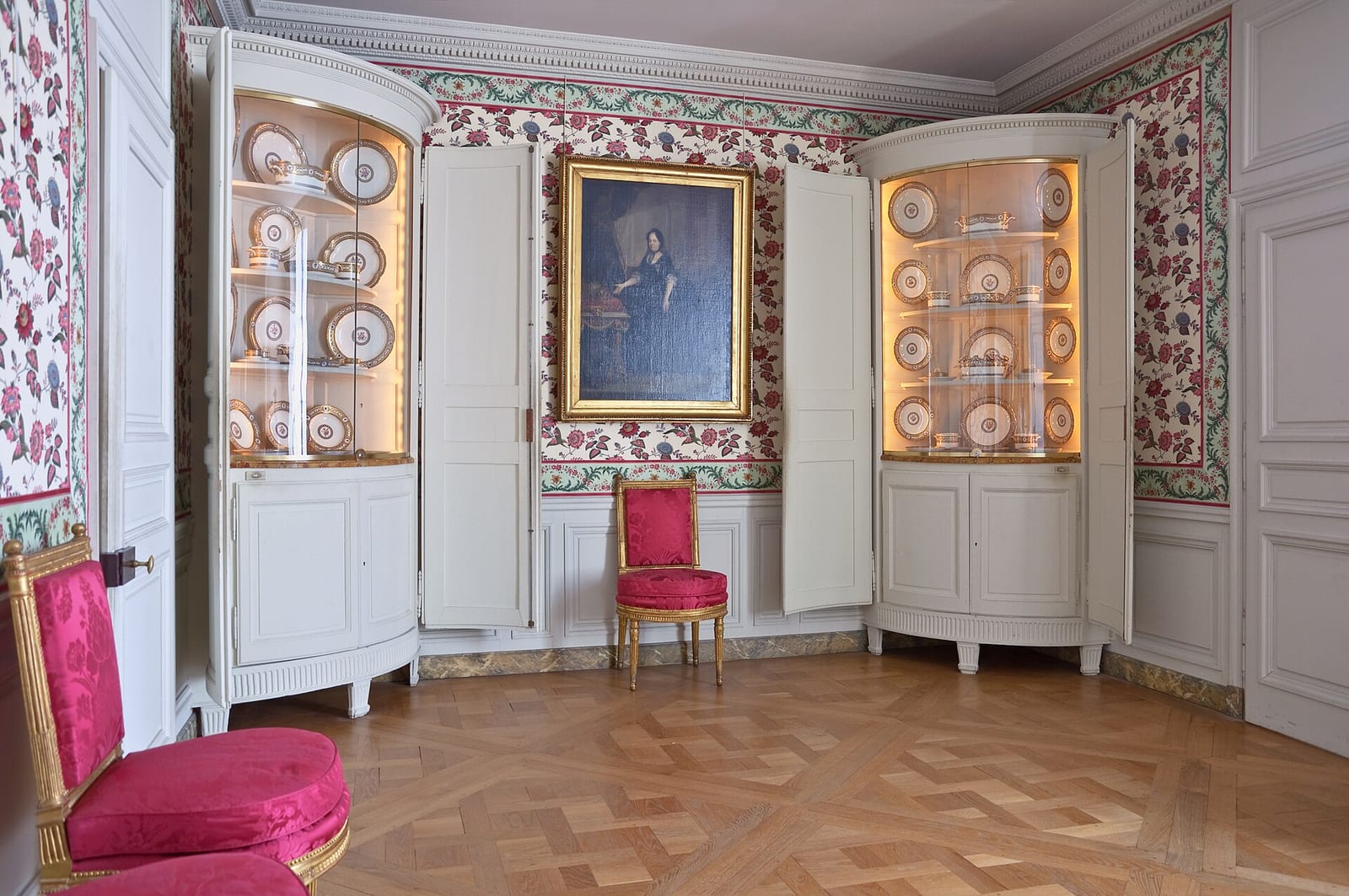 Small dining room in the Queen’s private apartments at Versailles, white panelling, parquet floor and a single portrait between two china cabinets.