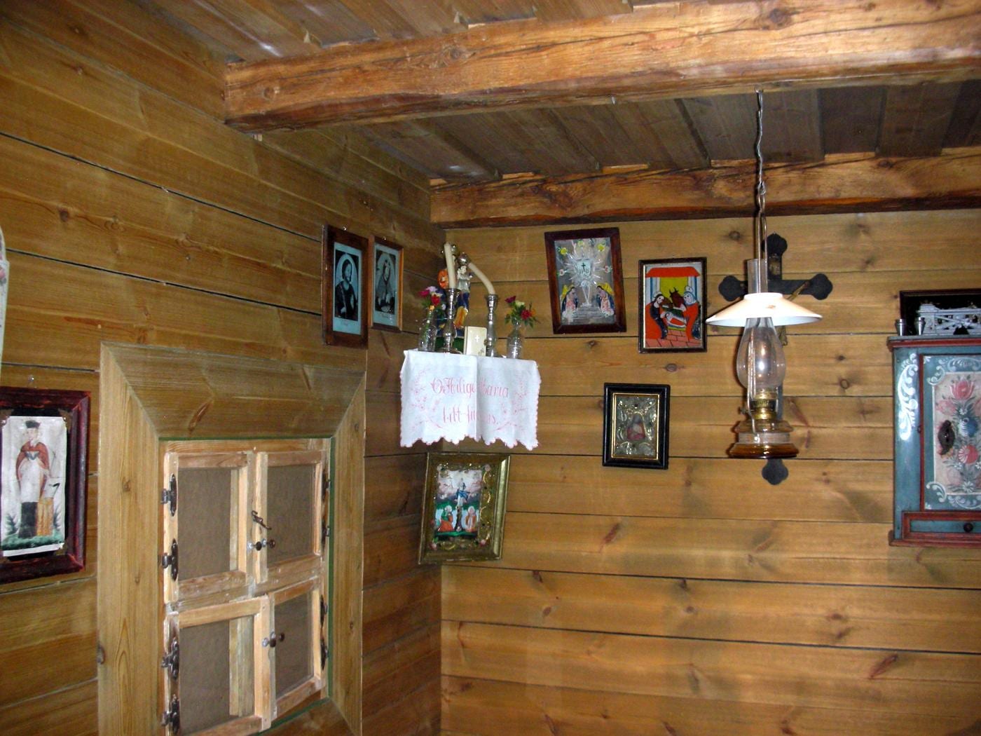 Wood-panelled farmhouse corner with crucifix and small framed pictures in a Herrgottswinkel