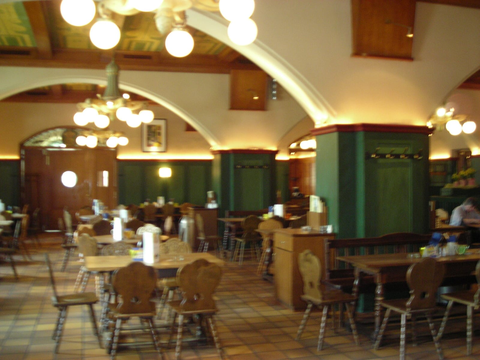 Vaulted dining hall of the Hofbräukeller in Munich with wooden tables and green panelling