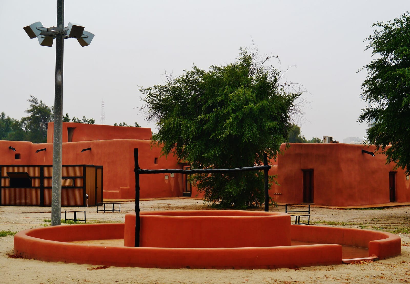 Inner courtyard of the Red Fort (al-Qasr al-Ahmar) in Al Jahra, Kuwait, with mud-plaster walls, wooden beams and bright sky, December 2022.