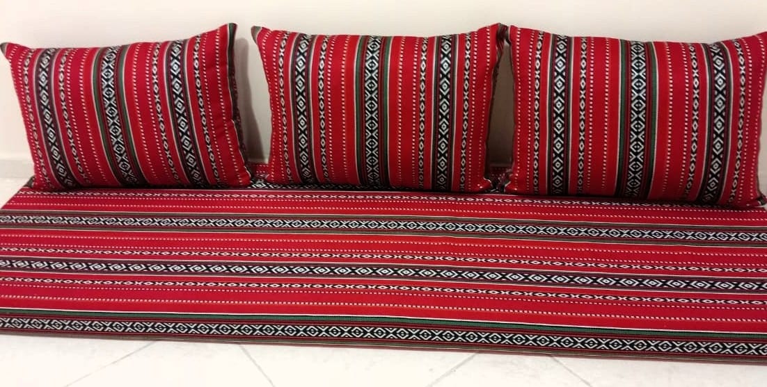 Low majlis seating upholstered in red, black and white Sadu-pattern weaving, photographed in the United Arab Emirates in August 2025.