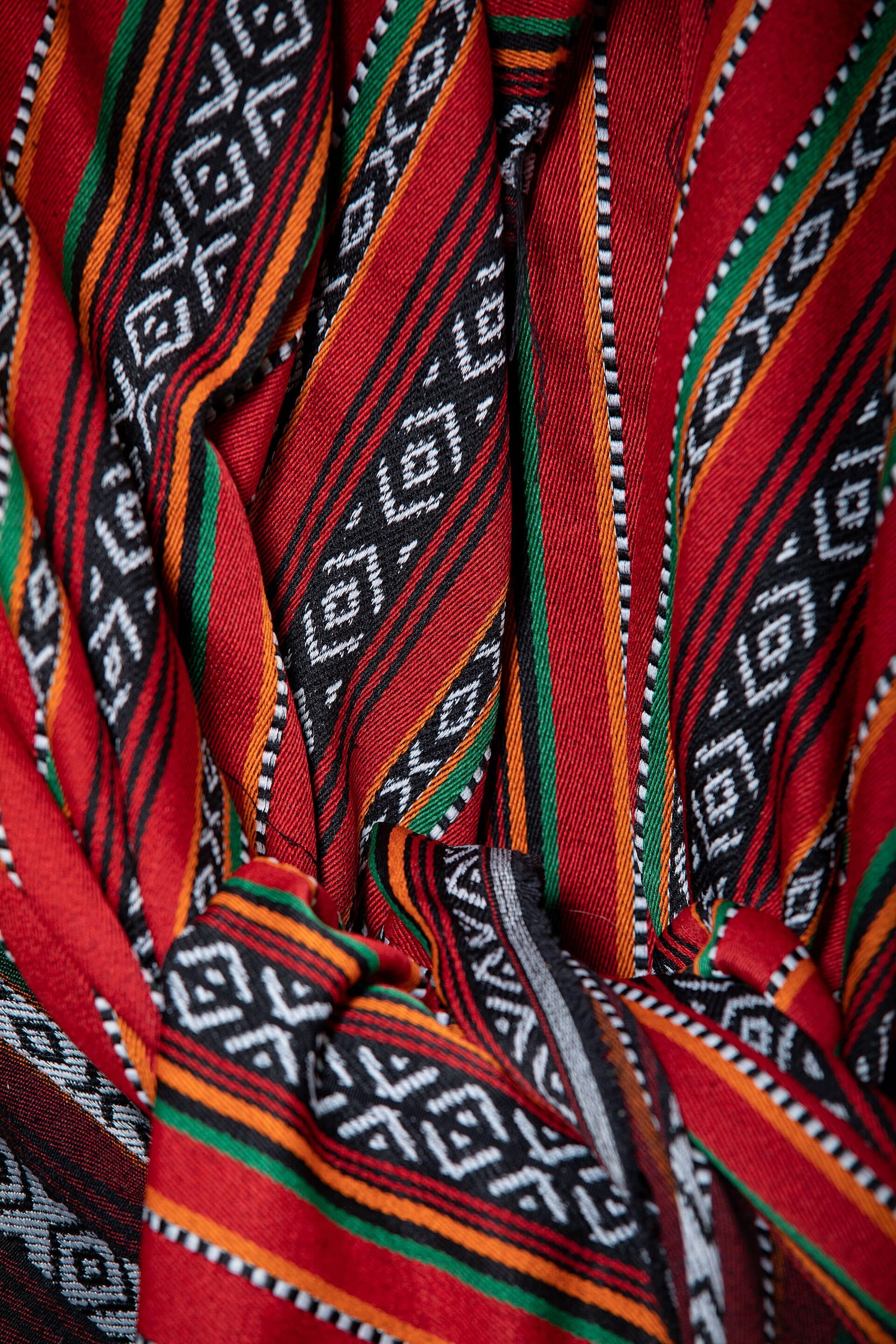 Close-up of a hand-woven Sadu-style textile with bands of red, black and white geometric diamonds and chevrons, from a private collection.