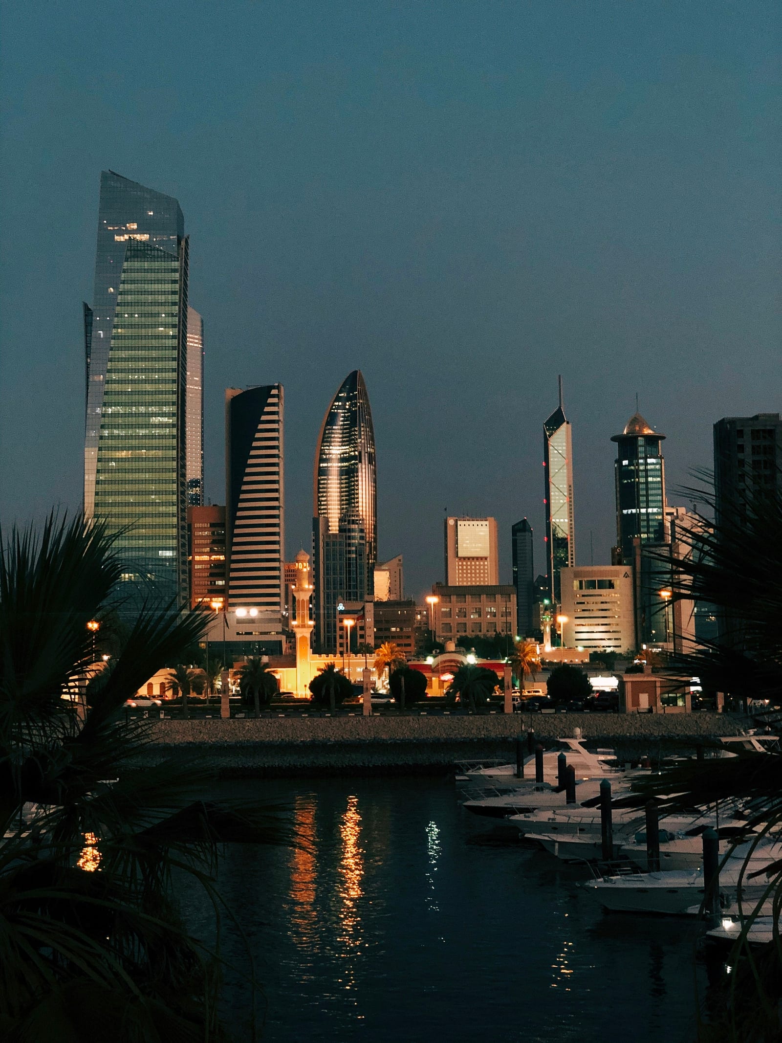 Kuwait City towers glowing at night across the water from the Souq Sharq marina, photographed 19 August 2020.